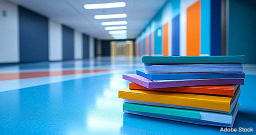 Ein Stapel bunter Bücher auf dem Flur einer Schule.